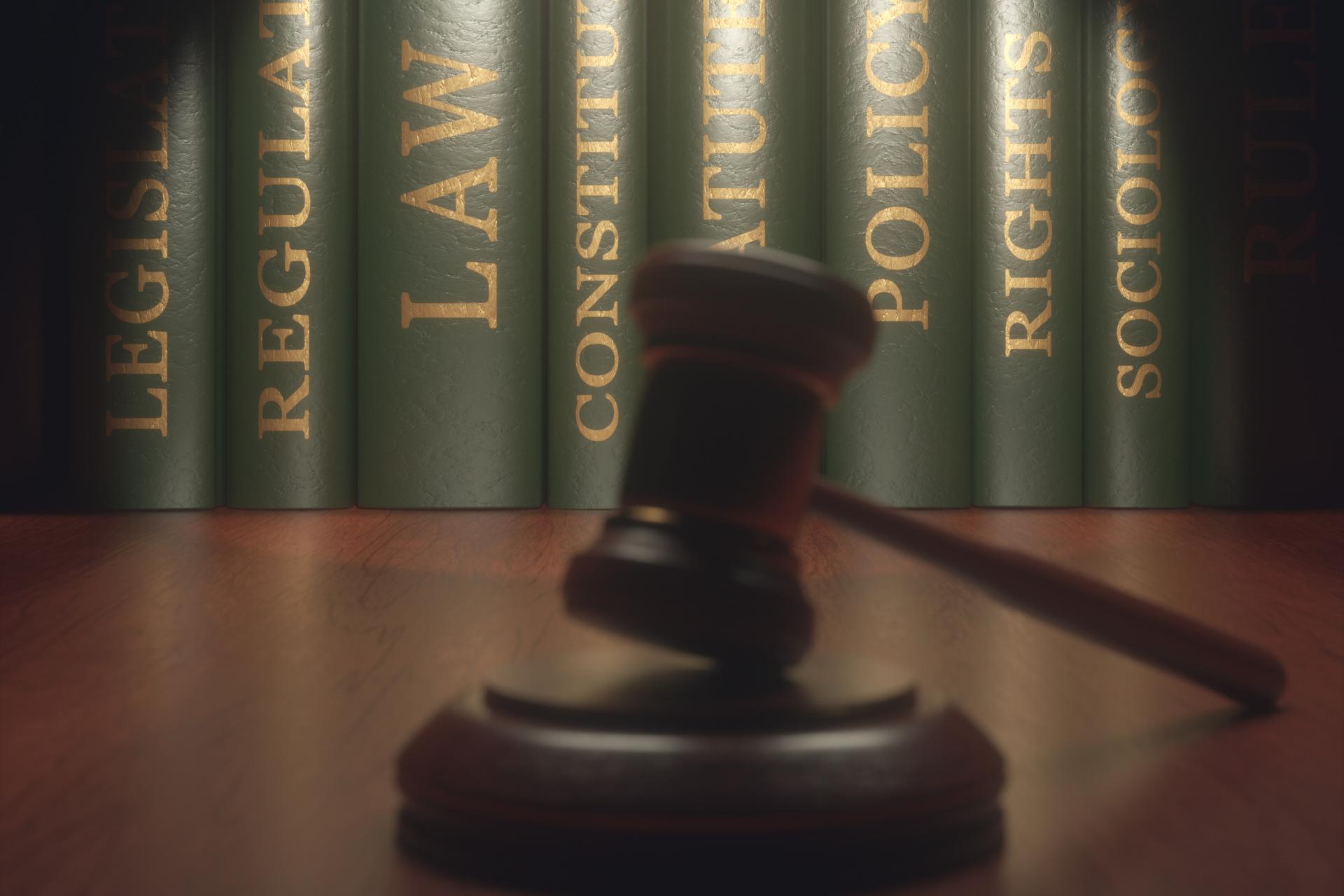 A judge’s gavel rests on a wooden surface in front of legal books labeled with terms like law, constitution, regulation, policy, rights, and Trucking Accident Lawyer.