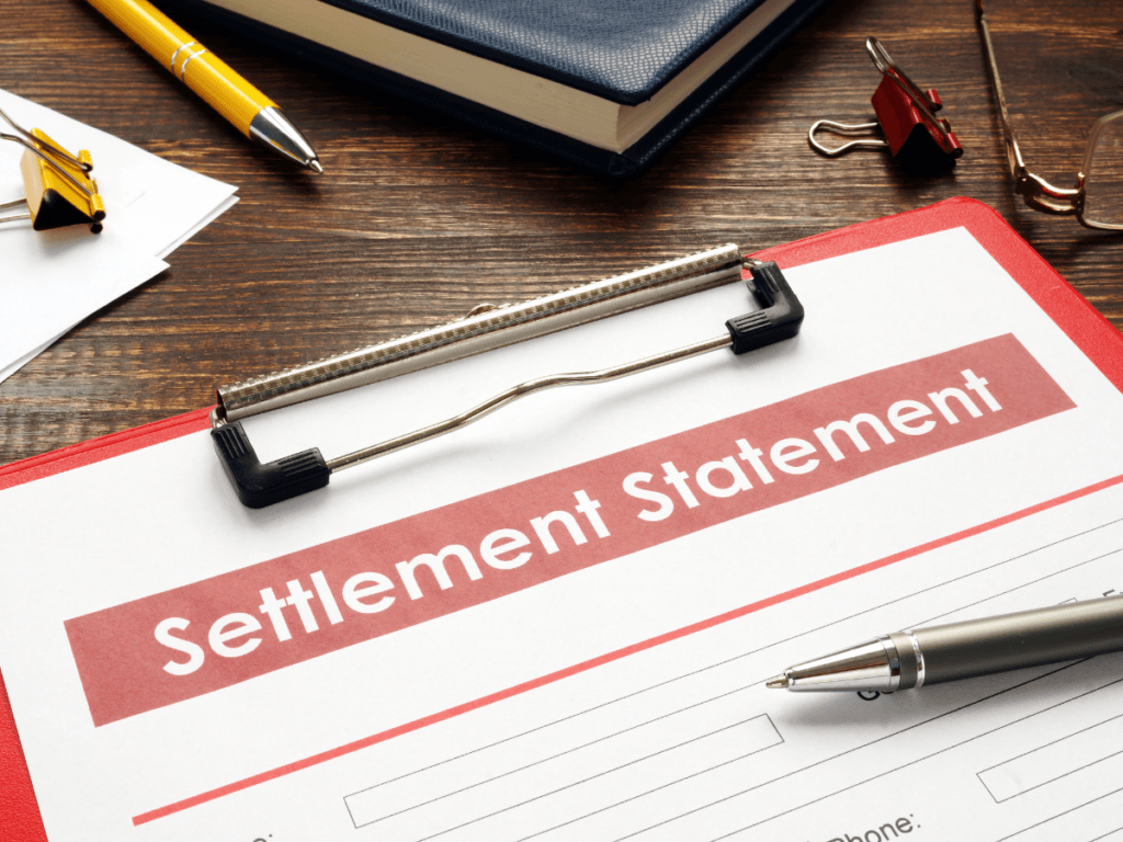 A clipboard holds a form labeled “Settlement Statement” on a desk with a pen, notebook, and binder clips nearby—providing an organized space to evaluate settlement options during the decision making process.
